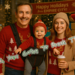 Gary Light stands with his daughter Abby and her baby, Teddy, posing in a festive holiday mall decorated for Christmas. Teddy sits in a front carrier strapped to Gary’s chest, and all three wear matching red Christmas sweaters. Green glowing text across the image reads, “Dad, You’re Going To Break That.”